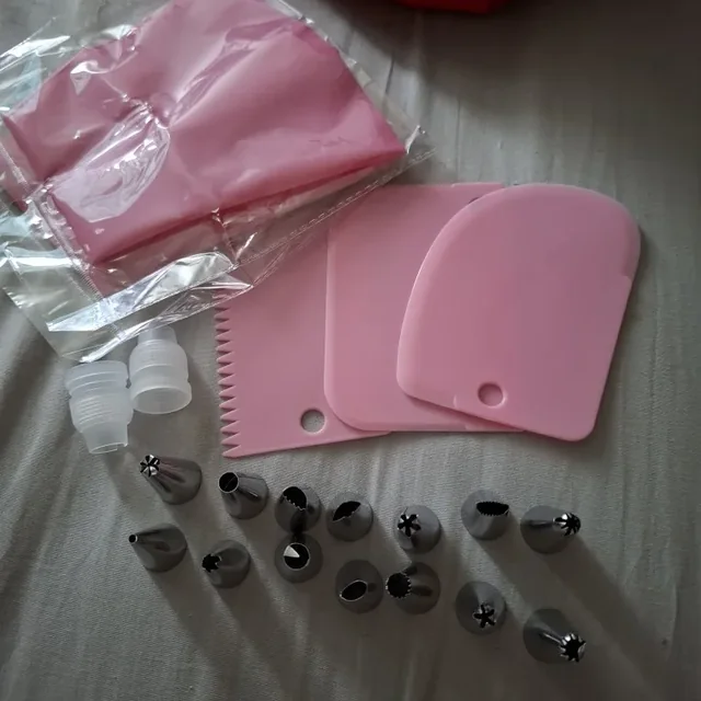Kit poche à douille rose déballé : lisseurs, coupleur et douilles inox posés sur un drap — photo d'un acheteur vérifié