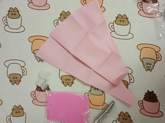 Poche à douille rose en silicone dépliée sur un tissu à motifs, avec son lisseur et le coupleur encore emballés — photo d'un acheteur vérifié